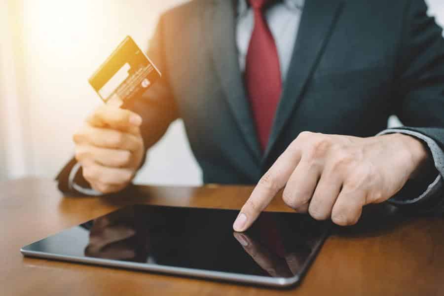 businessman holding a credit card while using tablet