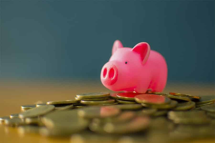 粉红色的迷你小猪银行放在硬币顶部。