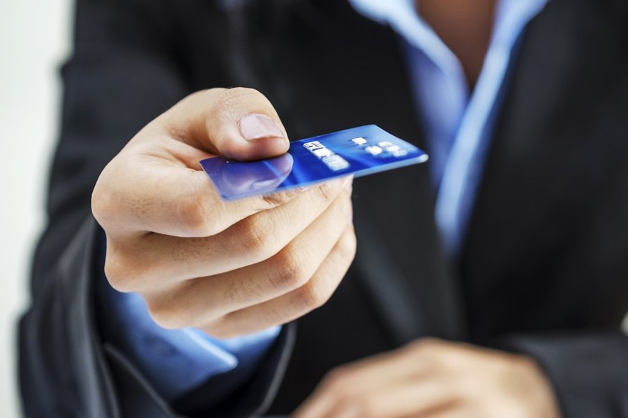 Businessman holding a blue credit card for payment.