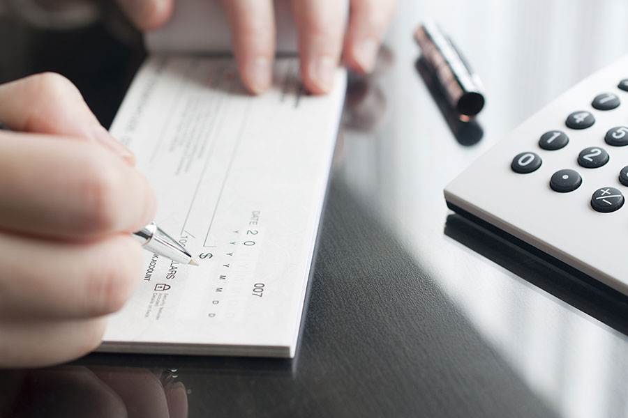 Close up shot of a hand signing a cheque.