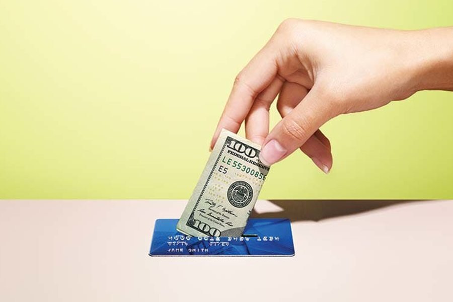 Woman holding a credit card and dollar bill.