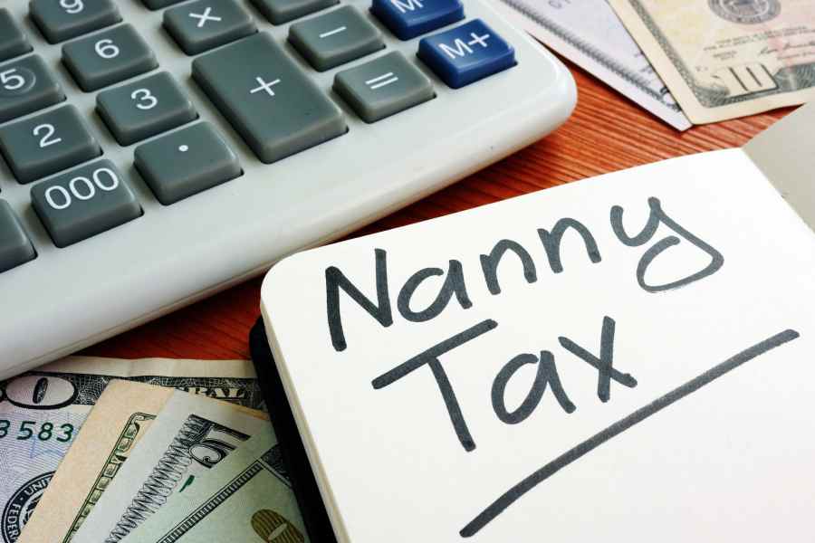 Nanny Tax written on a paper with calculator and money beside it.