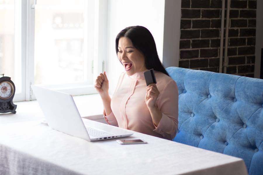 A woman happily looking through her laptop.