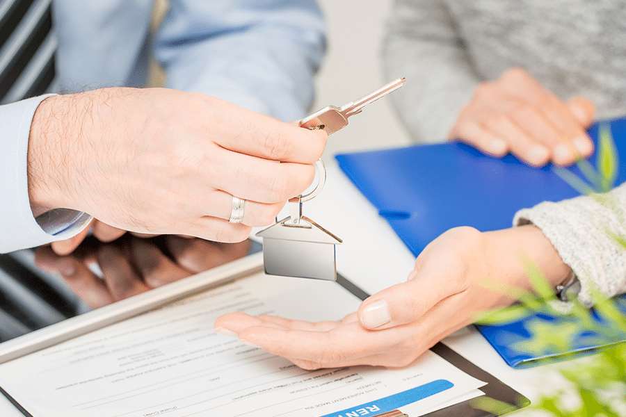 Real estate agent handling the house key to the new home owner.