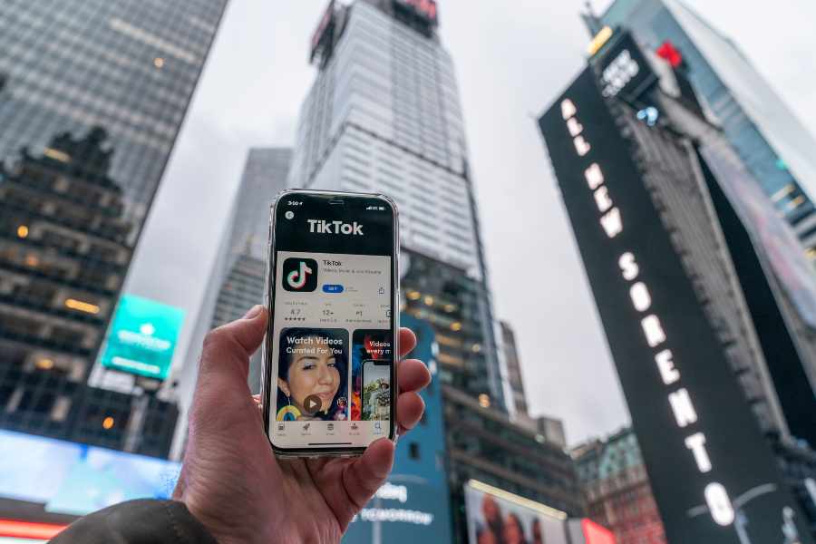 Close-up shot of a hand holding a phone with Tiktok account on the screen.