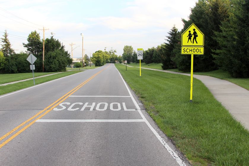 学校区域标志在一个黄色的柱子和一个写在路上。