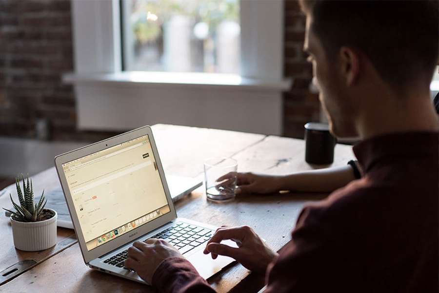 Close up shot of a guy working on his laptop.