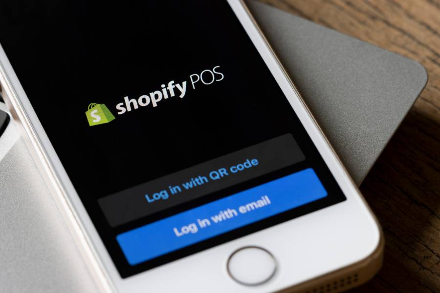 屏幕上有Shopify POS应用程序的智能手机。