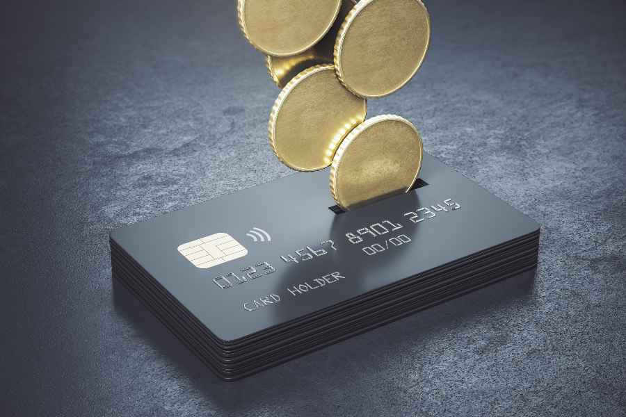 金属硬币绑定一堆黑色信用卡在抽象的黑暗表面。
