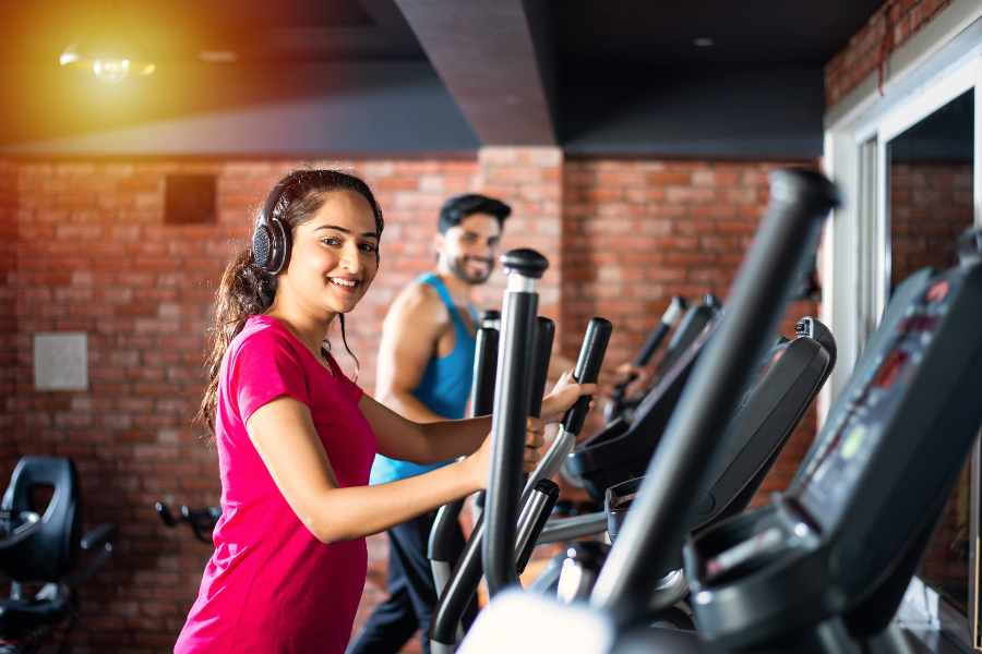 Man and woman doing cardio exercise in a fitness gym.