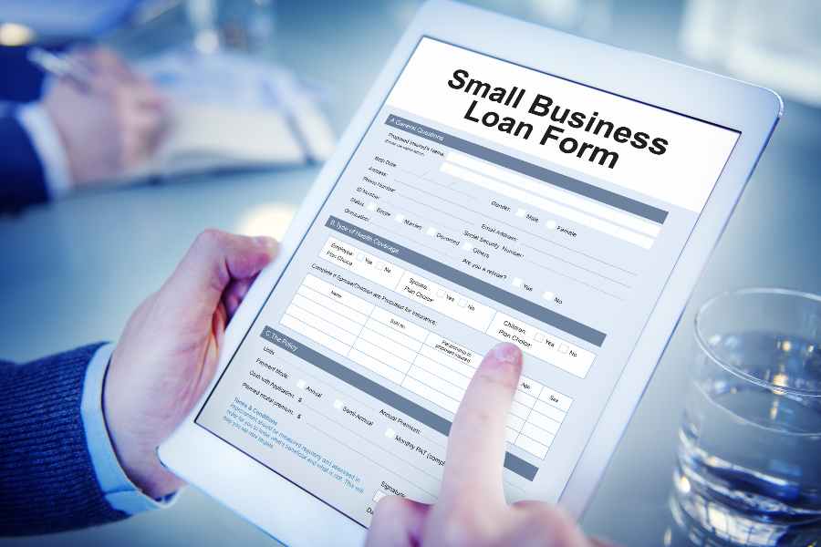 Man holding a tablet showing Small business loan form on the screen.