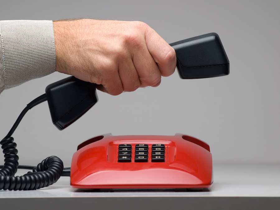 A hand answered a call on a red telephone.