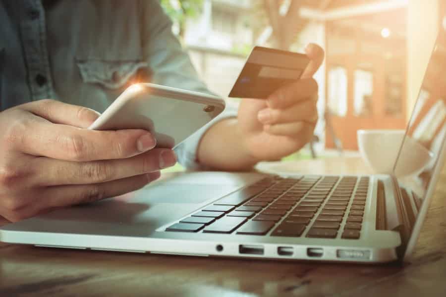 Man's hands holding smartphone and using credit card for online shopping.