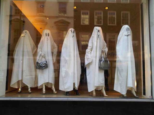 Mannequins covered in white sheets for a ghost-themed display at Stella McCartney store.