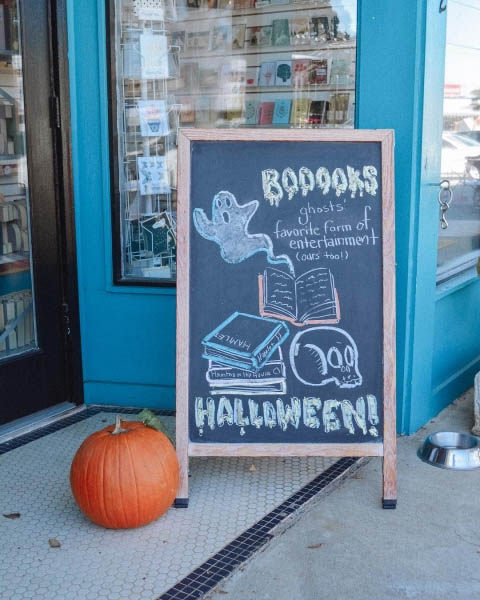 Sandwich board outside a bookshop with Halloween-themed messaging.